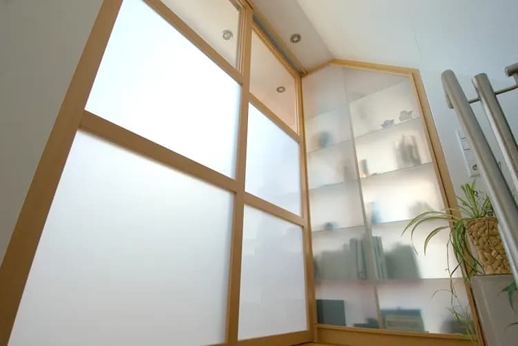Vitrinenschrank mit satinierten Glasfüllungen in hellem Holzrahmen