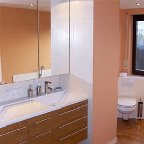 Badmöbel mit Holzfronten, Waschtisch und Spiegelschrank in apricotfarbenem Bad