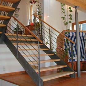 Treppe mit Stahlwangen und Holzstufen in einem offenen Wohnraum