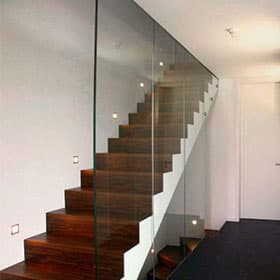 Treppe aus dunklem Holz vor einer raumhohen Glaswand