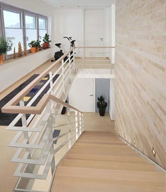 Schlanke Treppe mit weißen Stahlwangen und Holzstufen zwischen zwei Wohnebenen