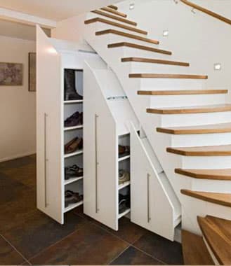 Weiße Treppe mit drei ausgezogenen Apothekerauszügen als Schuhschrank darunter