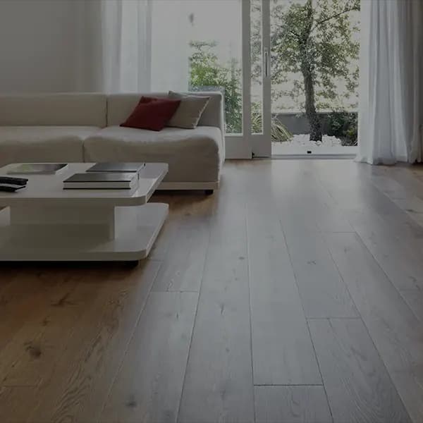 Wohnzimmer mit breiten Eichendielen, heller Sofalandschaft und bodentiefer Terrassentür