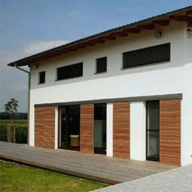 Weißes Wohnhaus mit Holzverkleidung und bodentiefen Fenstern zur Terrasse