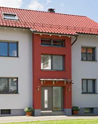 Modernisierte Hausfassade in Weiß und Rot mit neuer Haustür und neuen Fenstern
