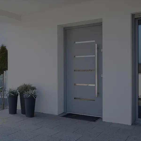 Moderner Hauseingang mit grauer Haustür und langem Edelstahlgriff
