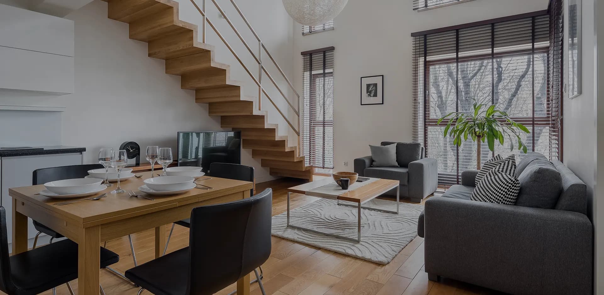 Modern eingerichtetes Wohnzimmer mit Essbereich und offener Holztreppe