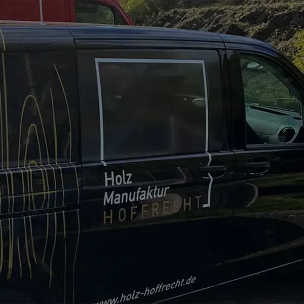 Schwarzer Firmentransporter von Holz Hoffrecht mit goldener Holzmaserung-Folierung