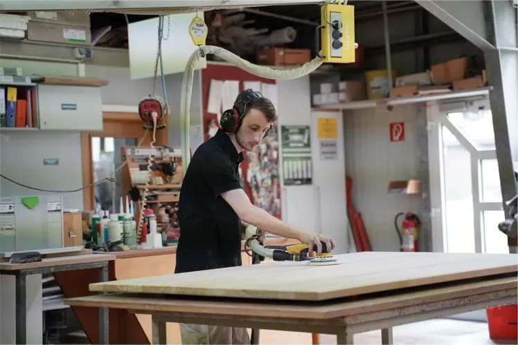 Mitarbeiter schleift eine Holzplatte in der Werkstatt von Holz Hoffrecht